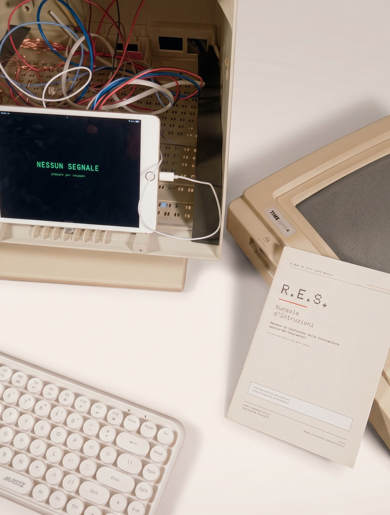 Inside the R.E.S. object: an iPad reading NESSUN SEGNALE inside an opened vintage monitor, next to a keyboard and the printed manual.